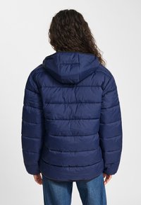 Mörkblå vadderad jacka med huva, med horisontella quiltade sektioner, slät textur och en ledig passform.