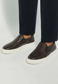 Brown woven leather slip-on sneakers with a white rubber sole. Features textured upper and sleek design, suitable for casual wear.