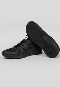 Baskets de sport noires avec une tige en mesh, semelle en caoutchouc et design texturé. Présente le logo "GORILLA WEAR" sur le côté et la semelle intérieure.