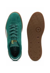 Zelene nubuk superge z belimi detajli, ravnim vezalkami, oblazinjenimi notranjimi podplati in teksturiranim rjavim gumijastim podplatom z okroglim vzorcem.