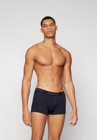 Sötétkék pamut boxer alsó fekete gumis derékkal, rajta fehér és piros "TOMMY HILFIGER" logóval. Egyszerű dizájn, testhezálló forma.