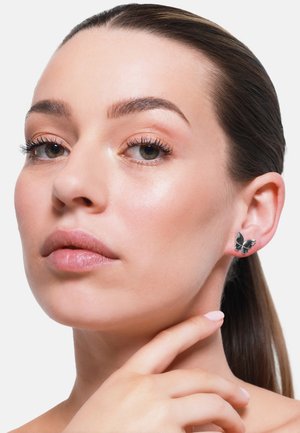 Silberne Schmetterlingsohrenringe mit einem detaillierten Design und strukturierten Flügeln, elegant vor einem neutralen Hintergrund präsentiert.