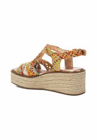 Sandalo espadrilla intrecciato multicolore con una piattaforma in juta spessa, caratterizzato da fasce incrociate e una fibbia regolabile alla caviglia.