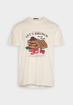 Camiseta de color crema con estampado temático de brunch que muestra gofres, panqueques, bayas y texto "Let's Brunch Sweet Fresh Waffles."