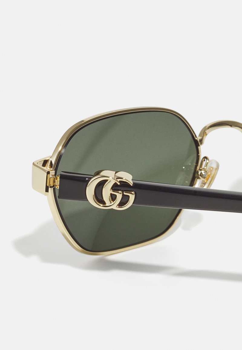 Gold-framed square sunglasses with dark green lenses and a black temple featuring a double-G logo accent. Glossy finish, sleek design.