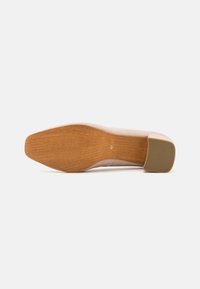 Pantof suede de culoare bej deschis, cu vârful rotunjit, tocul moderat bloc și o talpă din cauciuc texturat de culoare maro. Mărimea 41 este marcată pe talpă.