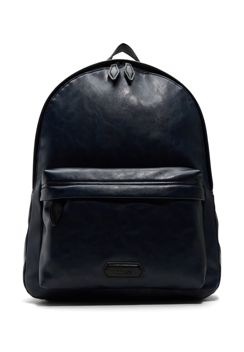 Sac à dos en cuir bleu marine avec une texture lisse, une forme arrondie, une poche frontale zippée et deux zips en haut. Présente un accent de logo subtil.