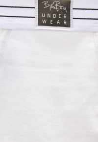 Λευκή ζώνη μέσης με μαύρες ρίγες και μαύρη ετικέτα που γράφει "Billy Boy Underwear" σε λευκό ύφασμα από κάτω.