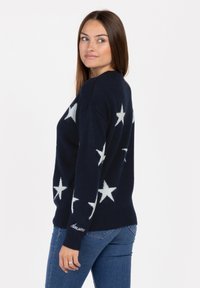 Navy Pullover mit weißem Sternmuster, runder Halslinie und "Awesome"-Textdetail am Saum. Der Stoff wirkt weich und strukturiert.