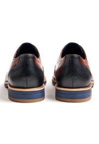 Ruskeat ja mustat nahkakengät, joissa on sileä viimeistely, teksturoitu musta kanta ja sininen sekä ruskehtava pohja. Suunniteltu pyöreällä mallilla.