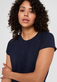 Granatowa koszulka z krótkim rękawem, wykonana z miękkiego i lekkiego materiału. Posiada okrągły dekolt oraz delikatne detale szwowe na ramionach.