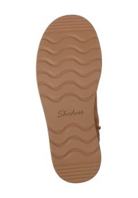 Suela de zapato Skechers, de goma color beige con patrón de olas y surcos horizontales. Presenta un logo "Skechers" en relieve. Textura suave, diseñada para ofrecer tracción.