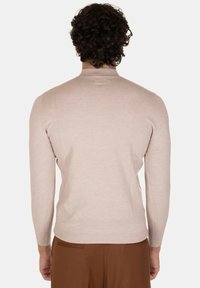Maglione beige a maniche lunghe con un design aderente e texture a coste, caratterizzato da un colletto alto e spalle senza cuciture.