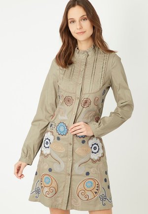 Vestido khaki de manga larga con botones en la parte delantera, intrincado bordado floral en azul y marrón, cuello con volantes y paneles texturizados en la parte superior.