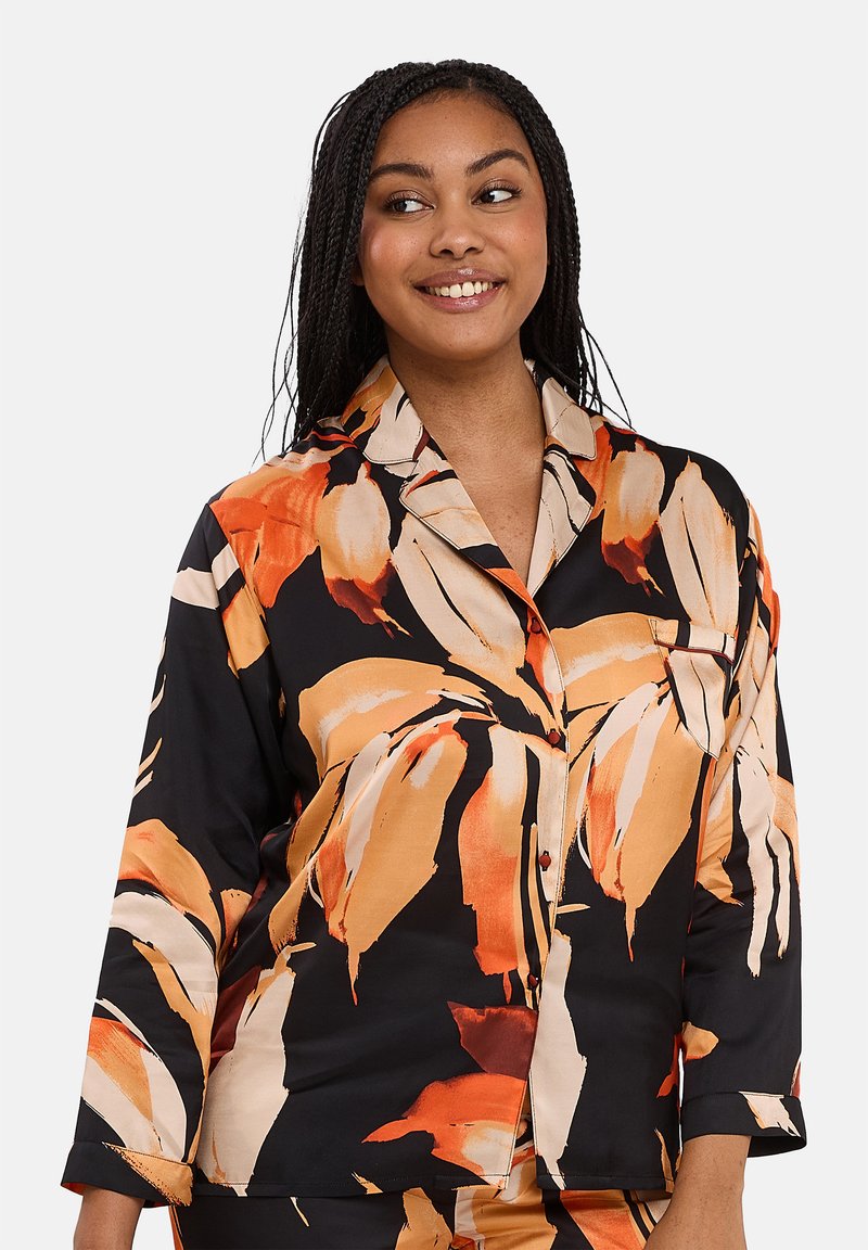 Chemise de pyjama à motifs noir et orange avec un col, des manches trois-quarts et une fermeture à boutons, ornée de fleurs.