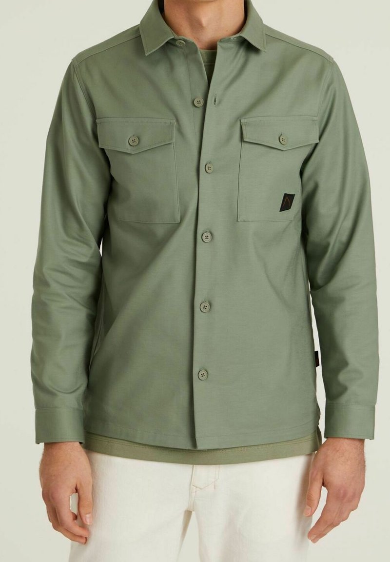 Groen overhemd met knopen en twee borstzakken, gemaakt van een gladde stof, met een puntig collor en een klein logo op de linkse zak.