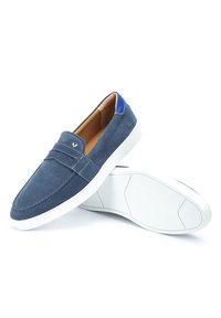 Zapatos de ante azul marino sin cordones con suelas de goma blancas. Cuentan con un acento azul en el talón, detalles de costura y un forro interior suave.
