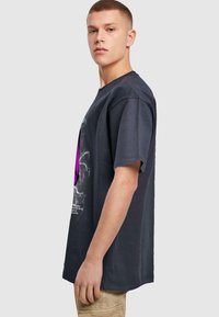 Donkergrijze katoenen t-shirt met korte mouwen, met een grafische print in paars en wit aan de voorkant. Rechte snit en een ontspannen pasvorm.