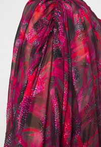 Tessuto fluido in vivaci tonalità di rosa e rosso, caratterizzato da un motivo floreale arricchito da discrete paillettes e dettagli testurizzati.