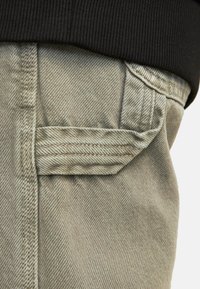 Bežna denimska tkanina z črnim rebrastim pasom. Ima zadnji žep s parom in podrobno šivanje. Gladka tekstura s klasičnim oblikovanjem.