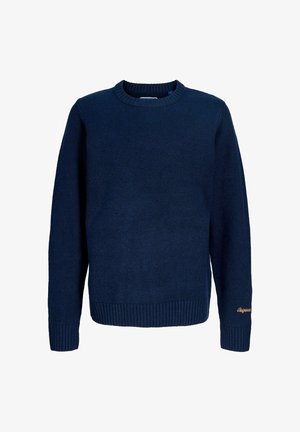 Sötétkék pulóver kerek nyakkal és bordás mandzsettával, világoskék széles szárú nadrággal és szürke sportcipővel párosítva. Tiszta, minimalista design.