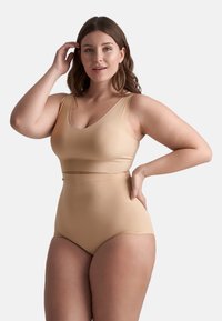 Completo da bagno beige a due pezzi con top a canotta a V e pantaloni alti, realizzato in materiale liscio e elasticizzato.