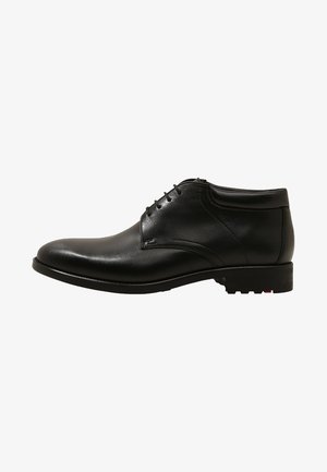 Chaussure habillée pour hommes en cuir noir avec fermeture à lacets et talon bas, vue de côté sur fond blanc.