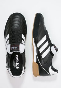 Zwarte leren sportschoenen met een witte drie-stripes ontwerp, gewatteerde tong en getextureerde rubberen outsole. Voorzien van een gevoerd kraag en logo-label.