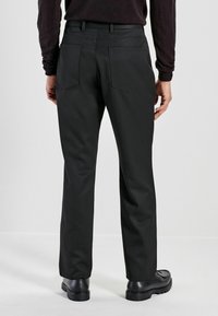 Black trousers with a straight-leg cut, featuring a smooth texture, two back pockets, and a clean waistband design. Worn with black shoes.