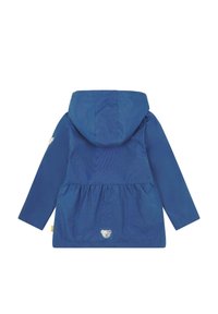 Giacca impermeabile blu con cappuccio, vita arricciata, maniche lunghe e patch con logo di un orso sul davanti. Texture morbida e vestibilità regolare.