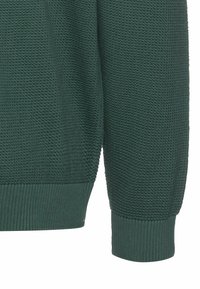 Dunkelgrüner Pullover mit strukturiertem Strickmuster und gerippten Bündchen. Das Material wirkt weich und hat eine lässige Passform.