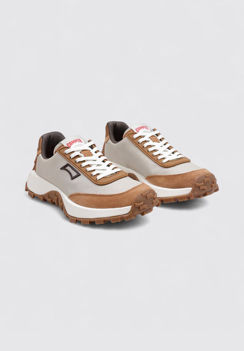 Herrskor i sneakersstil med ett överdel i ljusgrått tyg, bruna mockadetaljer, tjock vit sula och en brun gummisula med strukturerat mönster.