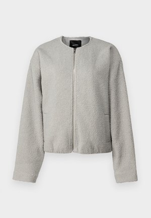 Hallhalli fliisjakk, millel on ümmargune kaelus, ees aukude sulgemine, pikad varrukad ja kaks küljetaskut. Pehme tekstuur; lühike disain.