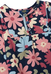 Hemd mit Blumenmuster auf navyfarbenem Hintergrund, mit rosa, blauen und grünen Blumen. Knopfverschluss mit gerippter Textur und rundem Halsausschnitt.