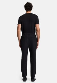 T-shirt da uomo nero a maniche corte abbinato a pantaloni neri a vestibilità comoda con vita elastica e tasche laterali. Design semplice e elegante.