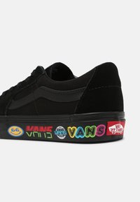 Baskets Vans noires avec logos et graphismes colorés Vans sur la semelle intermédiaire, comprenant un visage souriant, un globe et une étiquette "Off The Wall" au talon.