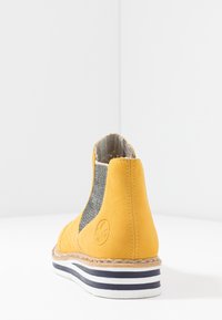 Żółte zamszowe botki za kostkę z elastycznymi panelami bocznymi, teksturowanym wykończeniem, szytą podeszwą oraz paskowaną gumową podeszwą. 