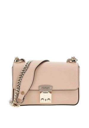 Sac à bandoulière beige de la marque Guess avec une sangle en chaîne dorée et une fermeture à clip gravée "GUESS EST. 1981" sur le rabat avant.