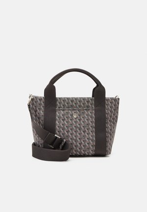 Petit sac fourre-tout avec des anses en tissu noir et une bandoulière ajustable, présentant un extérieur à motif géométrique et une poche avant avec fermeture à pression.