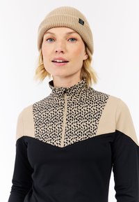 Sort og tan zip-up trøje med leopardmønstret design på den øverste halvdel, der har en høj krave. Strikket hue i beige farve.