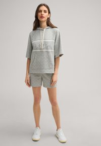 Grau gestelltes Set aus Kapuzenpullover und Shorts aus weichem Material, mit einer Fronttasche, Kapuze mit Kordelzug und einem 'JOOP!' Logo in der Mitte.