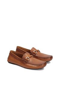 Mocasines de cuero marrón con puntera redondeada, detalles de costura y un acento metálico en la parte delantera. Suela flexible y textura suave.