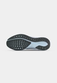 Semelle d’une chaussure de course grise et noire avec un motif de bande de roulement texturé incluant des zones de préhension en forme de losange et un logo Nike près du talon.
