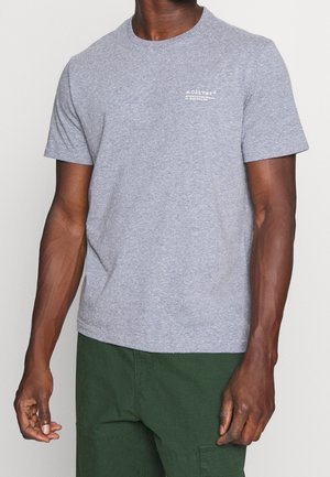 Grå bomuld T-shirt med korte ærmer, rund halsudskæring og hvidt logo trykt på venstre bryst. Kombineret med grønne cargoshorts.