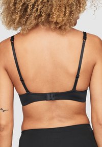 Zwarte onderwired bra met verstelbare bandjes, gladde stof en haak- en oogsluiting aan de achterkant. Minimalistisch ontwerp, geen zichtbare patronen.