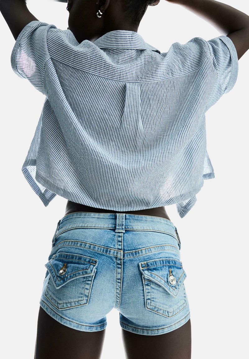Blå och vit randig kortärmad skjorta, i kombination med ljusblå denimshorts med bakfickor och knappdetaljer.