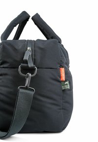 Black padded bag with dual handles and detachable shoulder strap, featuring tags stating eco-friendly materials and plastic bottle recycling.