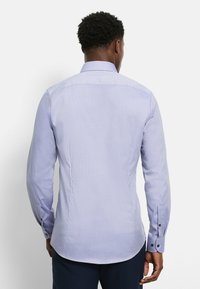 Himmelblaues langärmliges Hemd mit strukturiertem Muster, spitzem Kragen und geknöpften Manschetten. Taillierte Passform mit abgerundetem Saum.