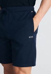 Pantalones cortos azul marino de tejido acanalado, con cintura elástica y cordón, bolsillos laterales y un pequeño logo blanco de "BOSS".