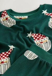 Donkergroene stoffen kleding met herhaalde feestelijke Santa gezichten die rode en witte geruite hoeden en witte baarden dragen.